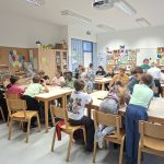 Učenci 5. a razreda sedijo za mizami in sodelujejo pri dejavnostih v učilnici.
